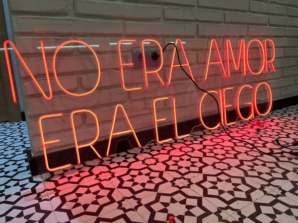 Neón rojo con una frase en dos líneas sobre suelo hidráulico